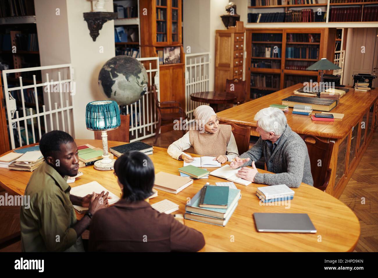 Hochwinkelporträt von verschiedenen Gruppe von Menschen studieren am runden Tisch in der klassischen College-Bibliothek, kopieren Raum Stockfoto