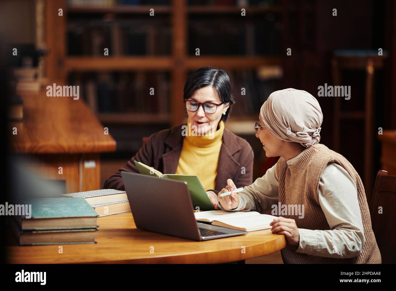 Warm getönte Porträt von zwei erwachsenen Frauen studieren zusammen in der klassischen College-Bibliothek, Copy Space Stockfoto