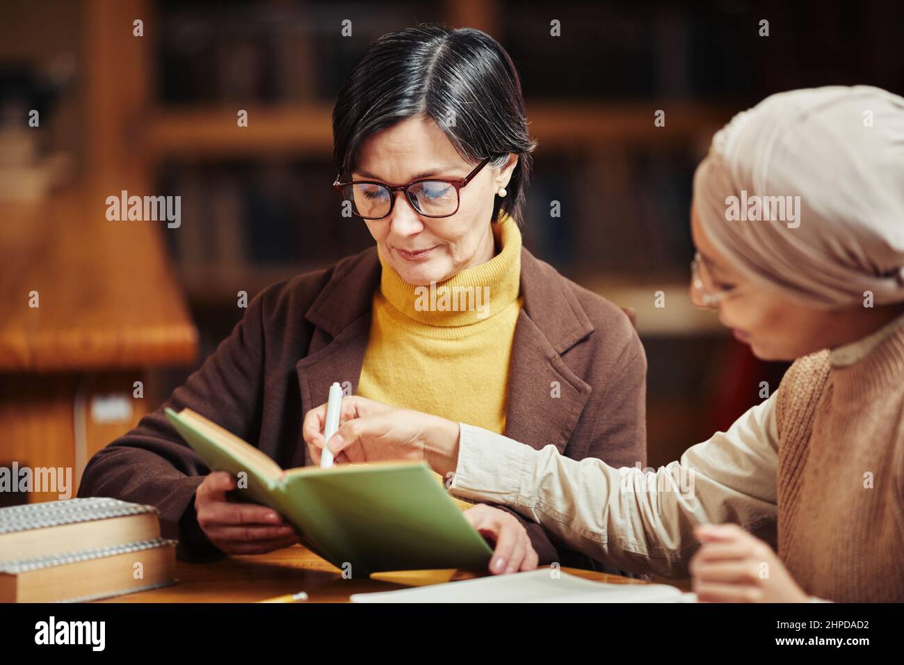 Warm getönte Porträt von zwei weiblichen erwachsenen Studenten Bücher zu lesen, während die Vorbereitung auf die Prüfung in der College-Bibliothek Stockfoto