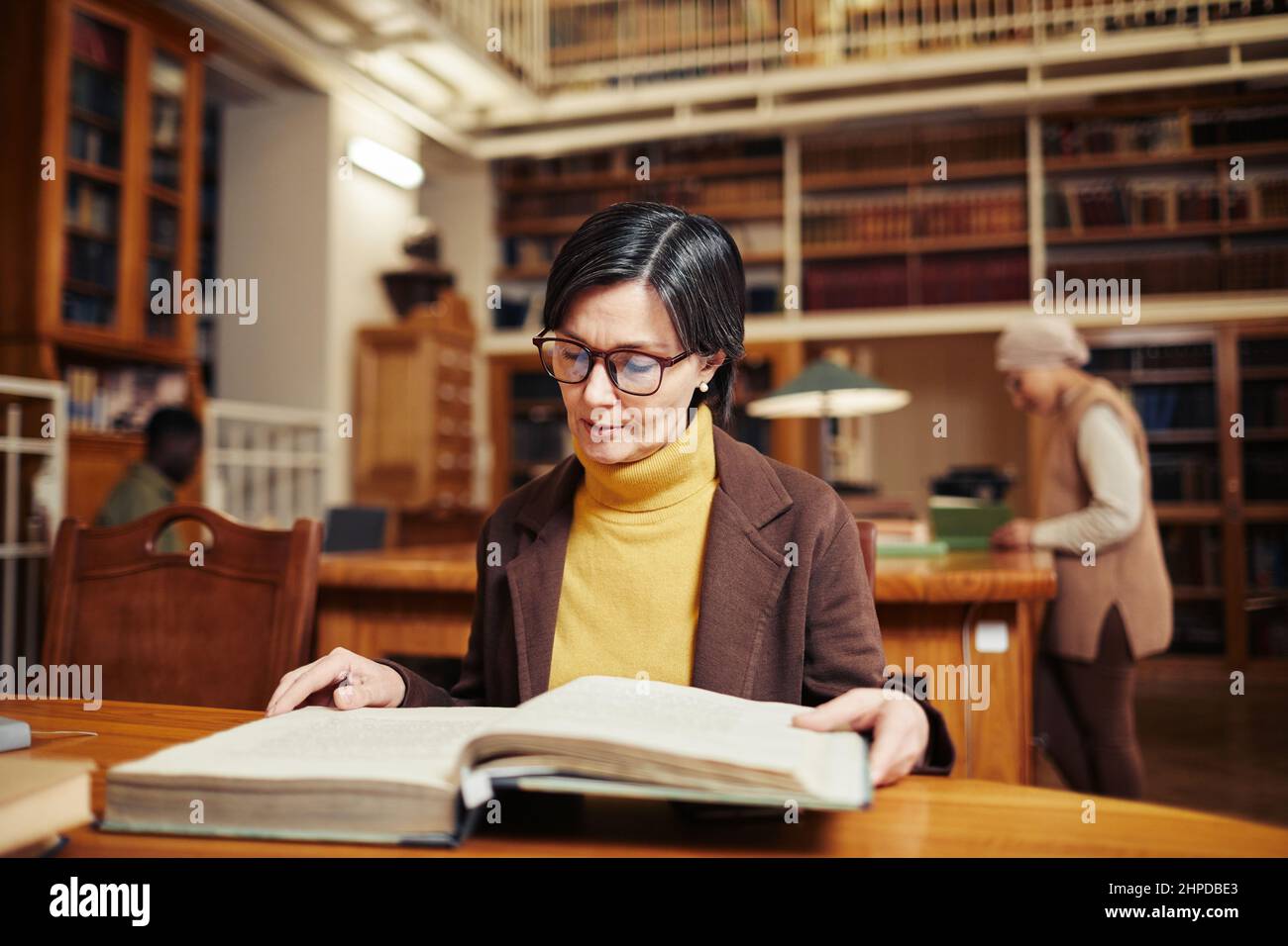 Warm getönte Porträt von erwachsenen Frau Buch in der klassischen College-Bibliothek zu lesen, während die Ausbildung nach vierzig Stockfoto