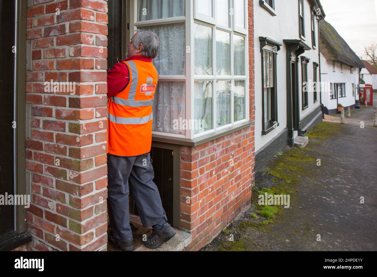 Royal Mail Postbote, der Briefe in einem Suffolk-Dorf, Großbritannien, ausliefert. Stockfoto