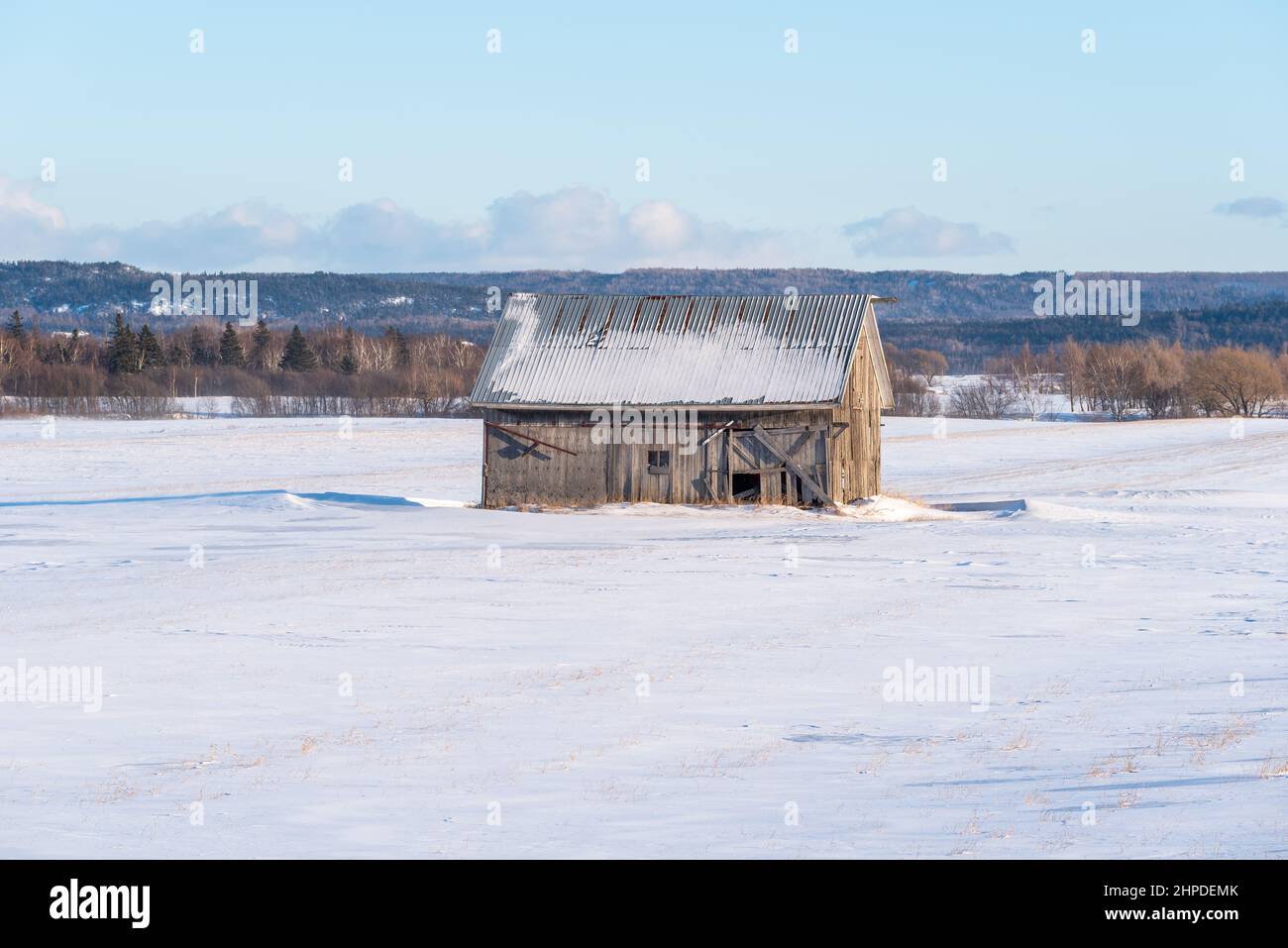 Im Winter, bei Sonnenuntergang, eine alte Scheune in einem verschneiten Feld im ländlichen Quebec, in der regionalen Gemeinde Kamouraska (Bas-Saint-Laurent, Quebec) Stockfoto