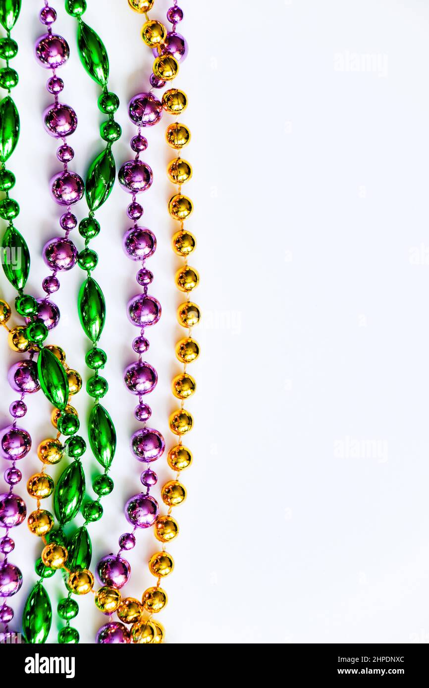 Mardi Gras Hintergrund. Bunte Perlen auf weißem Hintergrund. Fat Tuesday-Symbol. Festliche Dekorationen in Gold, Grün und Lila für Traditiona Stockfoto
