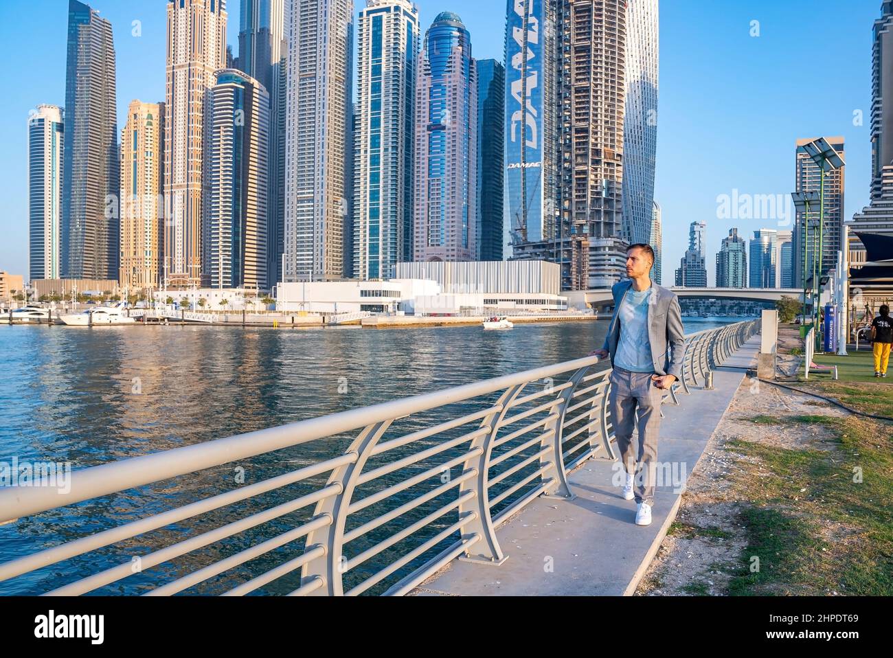 Junger Mann, der an der Promenade in Dubai Marina spazierengeht. Stockfoto