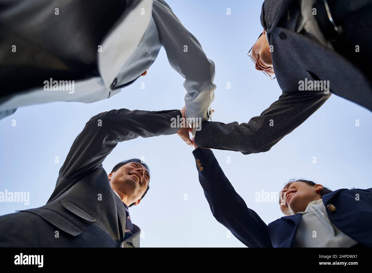 Eine Gruppe asiatischer Geschäftsleute, die ihre Hände zusammenlegen, um Teamgeist und Einheit zu zeigen Stockfoto