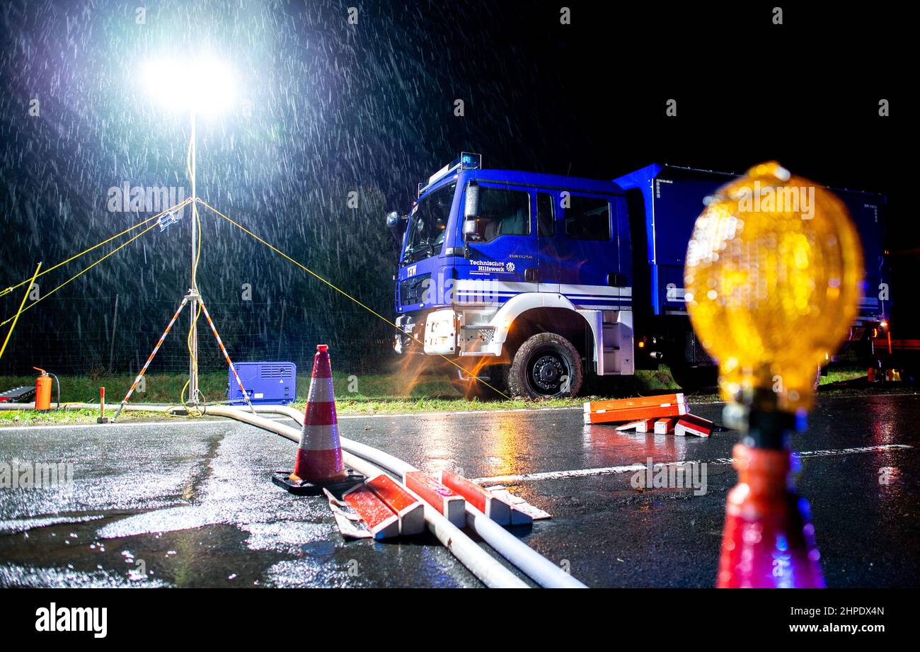 Bad Zwischenahn, Deutschland. 20th. Februar 2022. Bei starken Regenfällen steht ein Fahrzeug des Technischen Hilfswerks (THW) auf einer Straße. In der Nacht versuchen die Rettungskräfte, das Wasser aus einem überfluteten Hof abzupumpen und haben Schläuche über eine Länge von rund 600 Metern verlegt. Der Sturm „Antonia“ verursachte lokale Überschwemmungen aufgrund von Starkregen und andauerndem Starkregen. Quelle: Hauke-Christian Dittrich/dpa/Alamy Live News Stockfoto