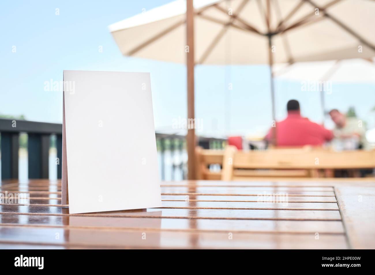 Blanke Poster auf einem Tisch auf der Terrasse eines Restaurants, im Sommer im Freien. Leerzeichen, um einen Text, ein Menü, Produkte, Werbeaktionen oder andere Informationen anzuzeigen Stockfoto