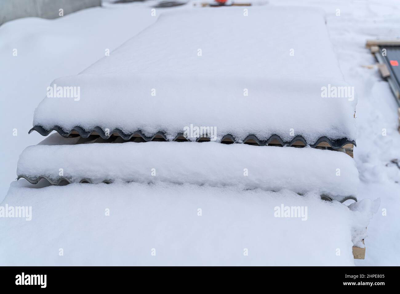 Stapel von gewölbtem Dachblech, draußen im Schnee gestapelt Stockfoto