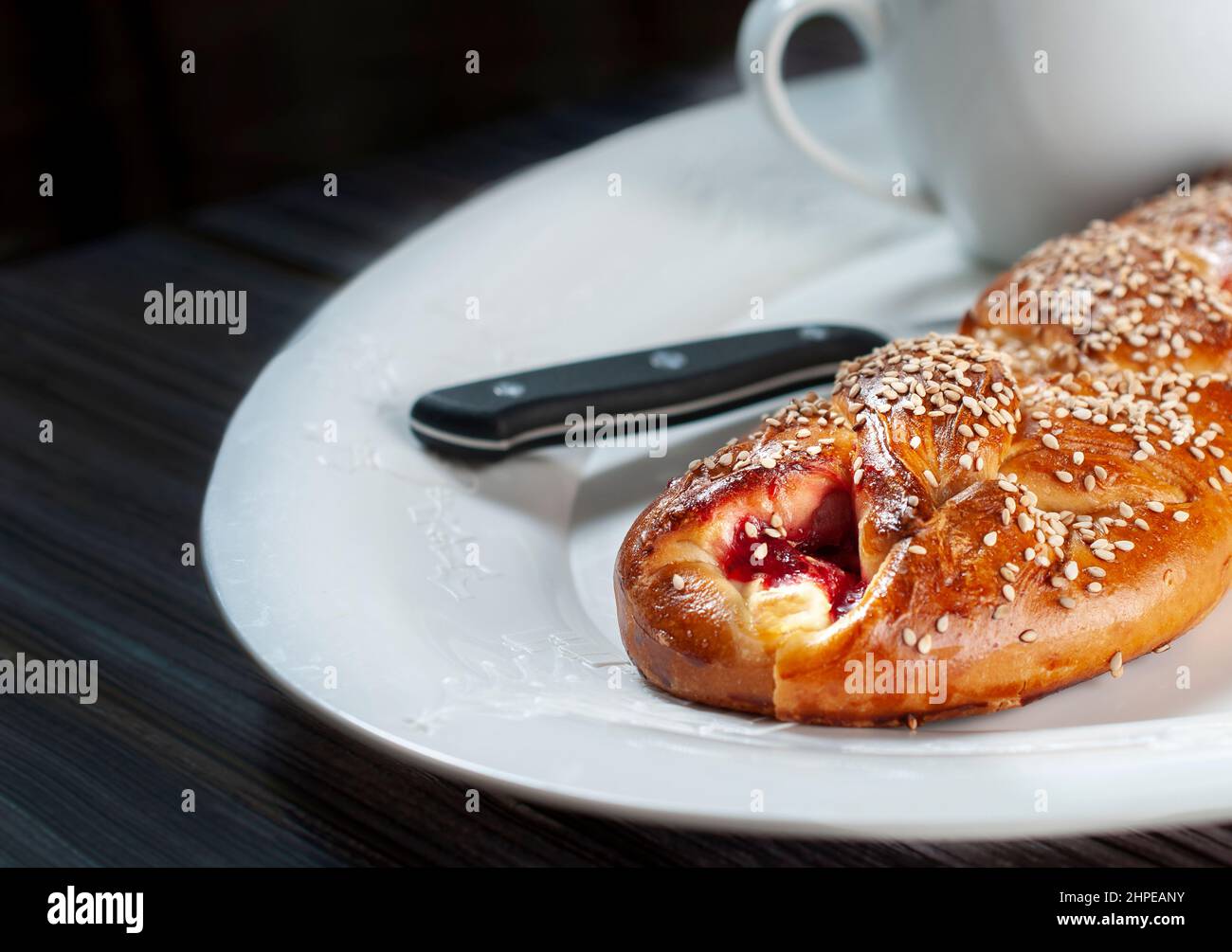 Süßes Brot gefüllt mit Erdbeermarmelade und Käse, mit Sesam, traditionellem mexikanischen Brot aus Oaxaca, auf einem weißen weihnachtsteller. Makro Stockfotografie