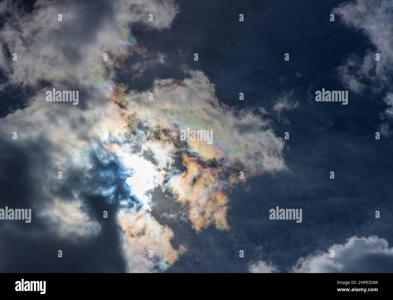 Dünne, wispy Wolken erzeugen Regenbogenmuster von gestreutem Sonnenlicht. Optisches Phänomen. Stockfoto