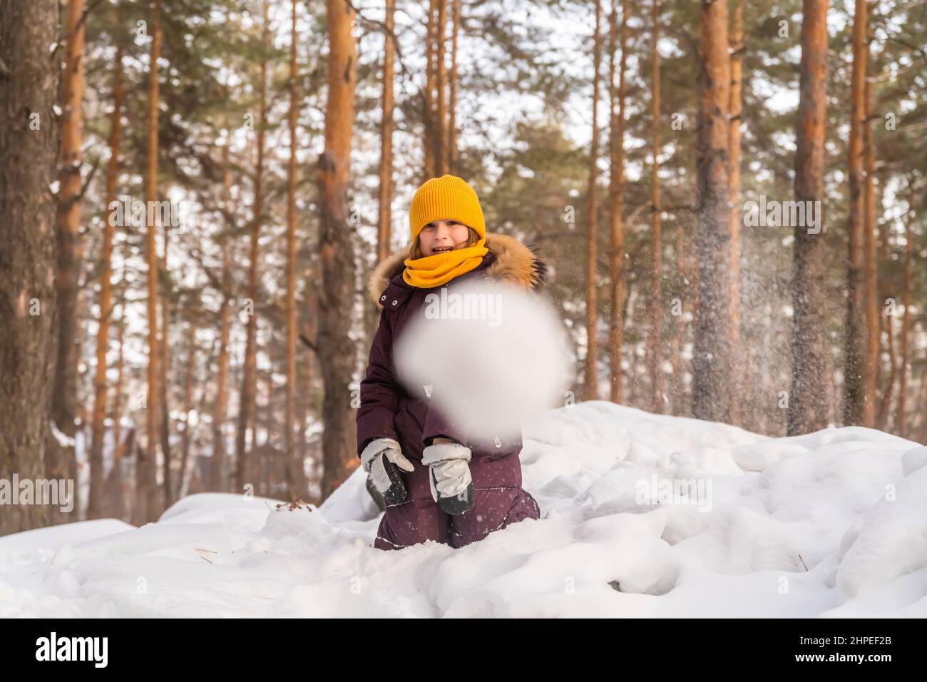 Nettes Mädchen im Winter Jumpsuit im Schnee spielen, wirft einen Schneeball Stockfoto