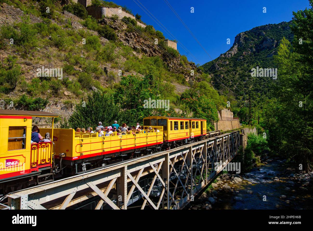 Der kleine gelbe Zug (Le Petit Train Jaune), der durch Villefranche-de-Conflent, Frankreich, fährt Stockfoto