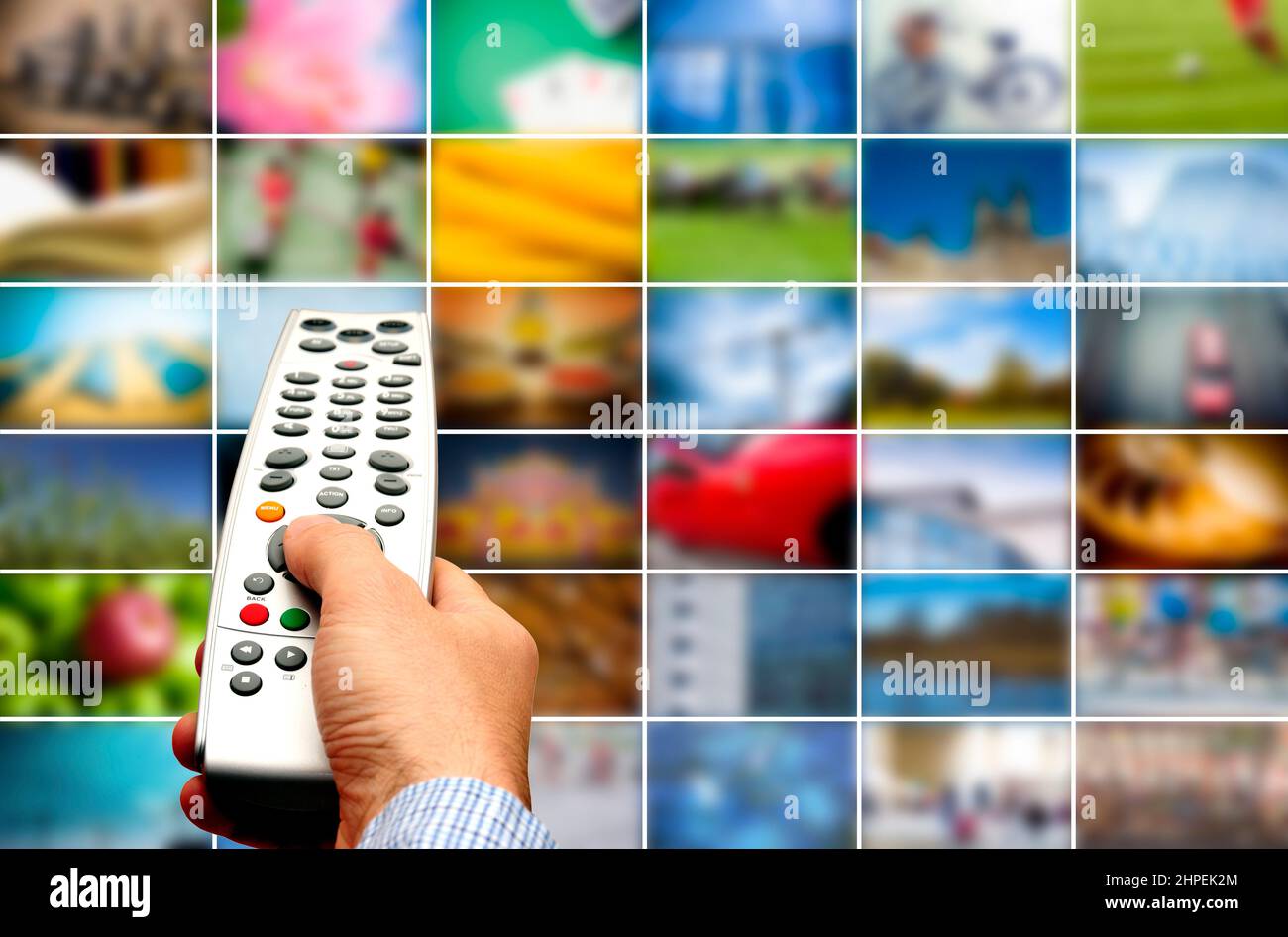 Hand mit Fernbedienung, die auf eine Wand aus Bildern, tv-Streaming und Multimedia-Konzept zeigt Stockfoto