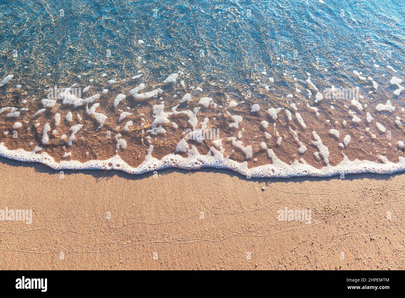 Wunderschöne Meereswelle an einem Sandstrand. Abstrakter Hintergrund, Ansicht von oben, freier Kopierbereich. Stockfoto