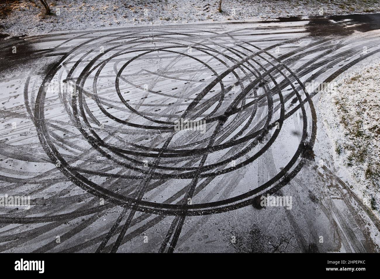 Abstrakte Kreise im Schnee, Autodrift-Skid-Markierungen auf der winterlichen Rennbahn. Stockfoto