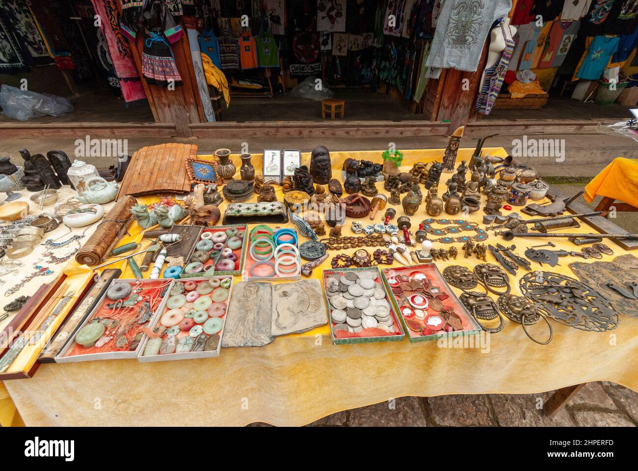 Tisch mit Souvenirs zum Verkauf in der Altstadt von Baisha, Yunnan, China im Jahr 2007. Verschiedene Gegenstände von Metallarbeiten bis hin zu Münzen und sogar Fossilien. Stockfoto