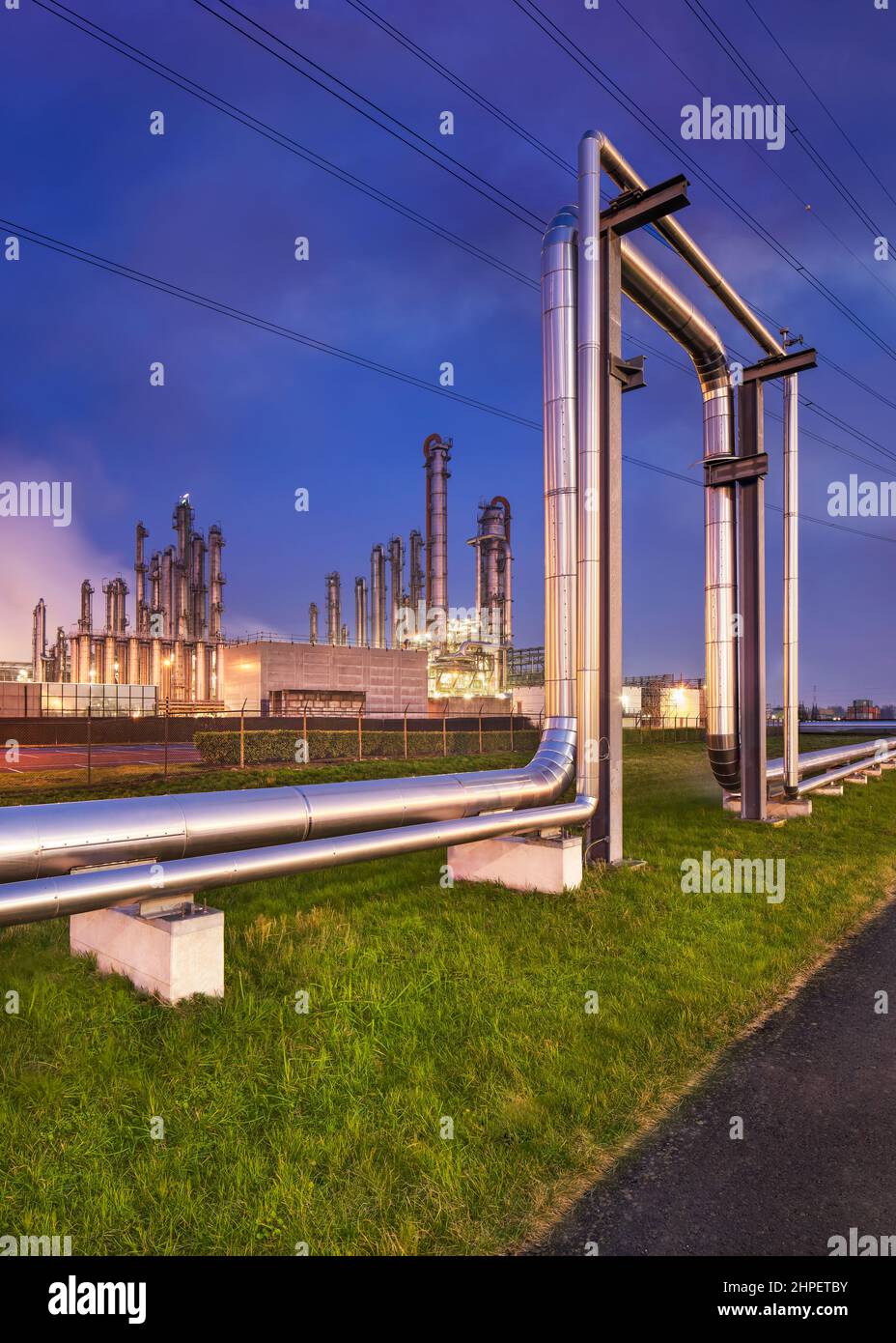 Bau mit Pipeline und beleuchteter petrochemischer Produktionsanlage in Twilight, Hafen von Antwerpen. Stockfoto