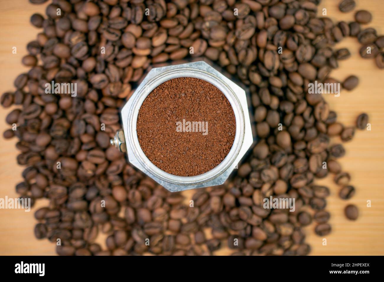 Kaffeemaschine mit Kochplatte, Moka Perkolator, gefüllt mit gemahlenem Kaffee, umgeben von Kaffeebohnen Stockfoto