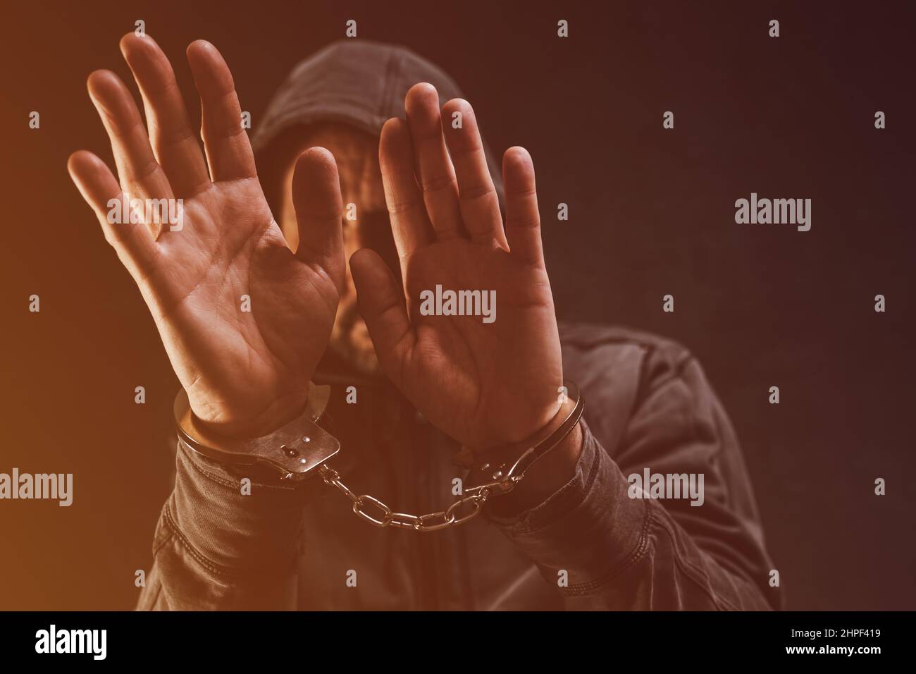 Festgenommene Verbrecher mit Handschellen, die das Gesicht verstecken, selektiver Fokus Stockfoto
