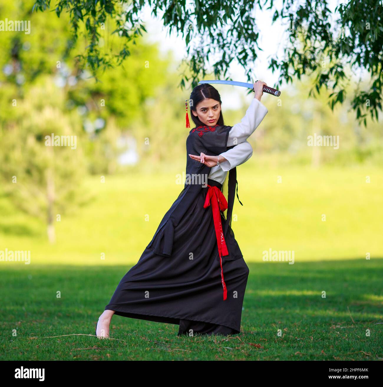 Junge asiatische Frau im traditionellen Kimono trainiert Kampftechniken mit Katana-Schwert, Samurai-Kriegermädchen Stockfoto