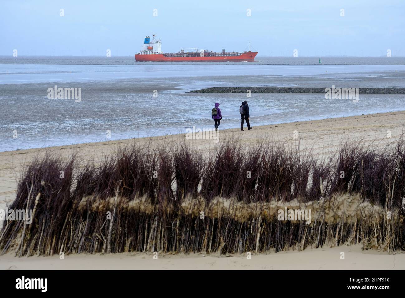 10.02.2022, Cuxhaven, Niedersachsen, Deutschland - zwei Spaziergaenger im Watt am Strand von Cuxhaven bei Ebbe an einem Wintertag im Februar am Rande Stockfoto
