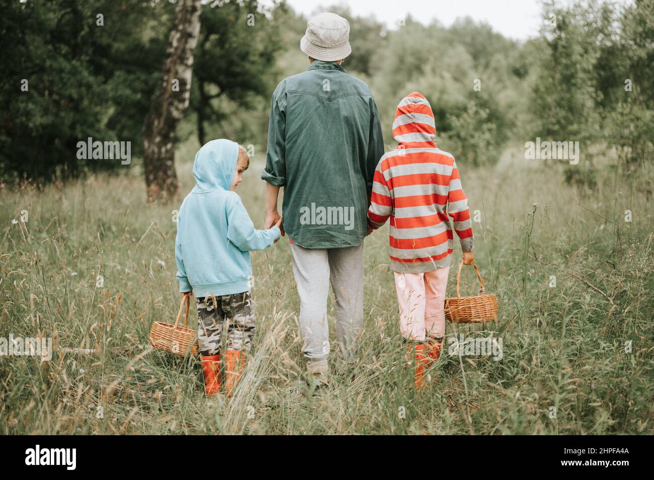 Kleine Kinder Pilzsammler gehen in den Wald oder Wald von der Hand mit ihrer Großmutter. Familie von Überlebenden sammelt eine wilde Pilzernte und Stockfoto