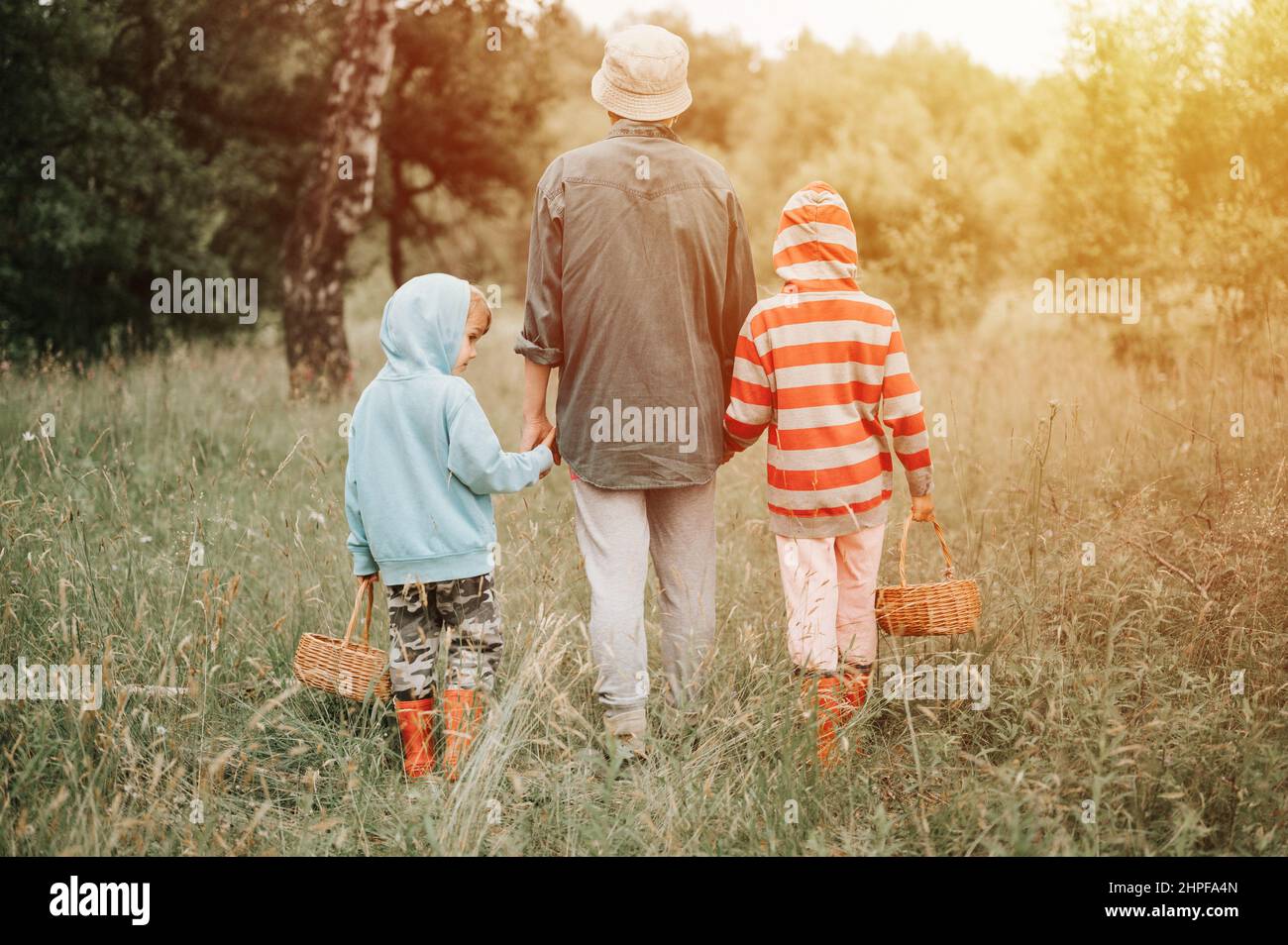 Kleine Kinder Pilzsammler gehen in den Wald von der Hand mit ihrer Großmutter. Familie von Überlebenskünstlern sammelt eine wilde Pilzernte und im Freien für Stockfoto