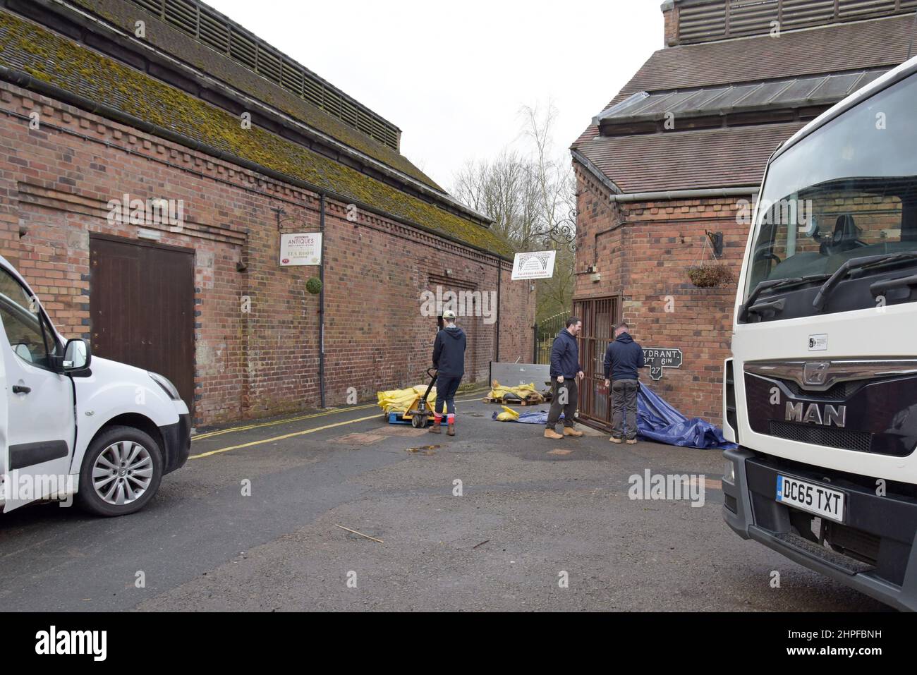 Ironbridge, Telford, Großbritannien. 21st. Februar 2022. Die Mitarbeiter von Ironbridge Interiors bereiten die Hochwasserschutzmaßnahmen vor, da der angrenzende Fluss Severn sich schnell in Richtung ihrer Werkstatt erhebt, die in den letzten zwei Jahren dreimal überflutet wurde. Die übermäßigen Niederschläge der letzten Woche durch Stürme haben dazu geführt, dass der Fluss Severn auf sehr hohe Niveaus ansteigt und die umliegenden Städte und das Land überflutet hat. Der Höhepunkt ist jedoch am Dienstagabend. G.P.Essex, Alamy Live Nachrichten Stockfoto