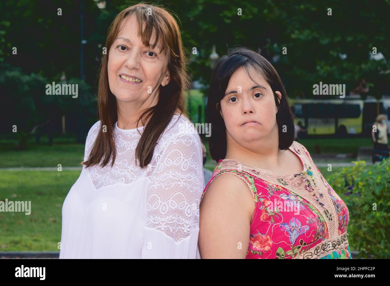 Porträt der kaukasischen lateinischen Mutter und Tochter zusammen auf einem Platz Blick auf die Kamera, Inklusion, Menschen mit Behinderungen und Lifestyle-Konzept. Stockfoto