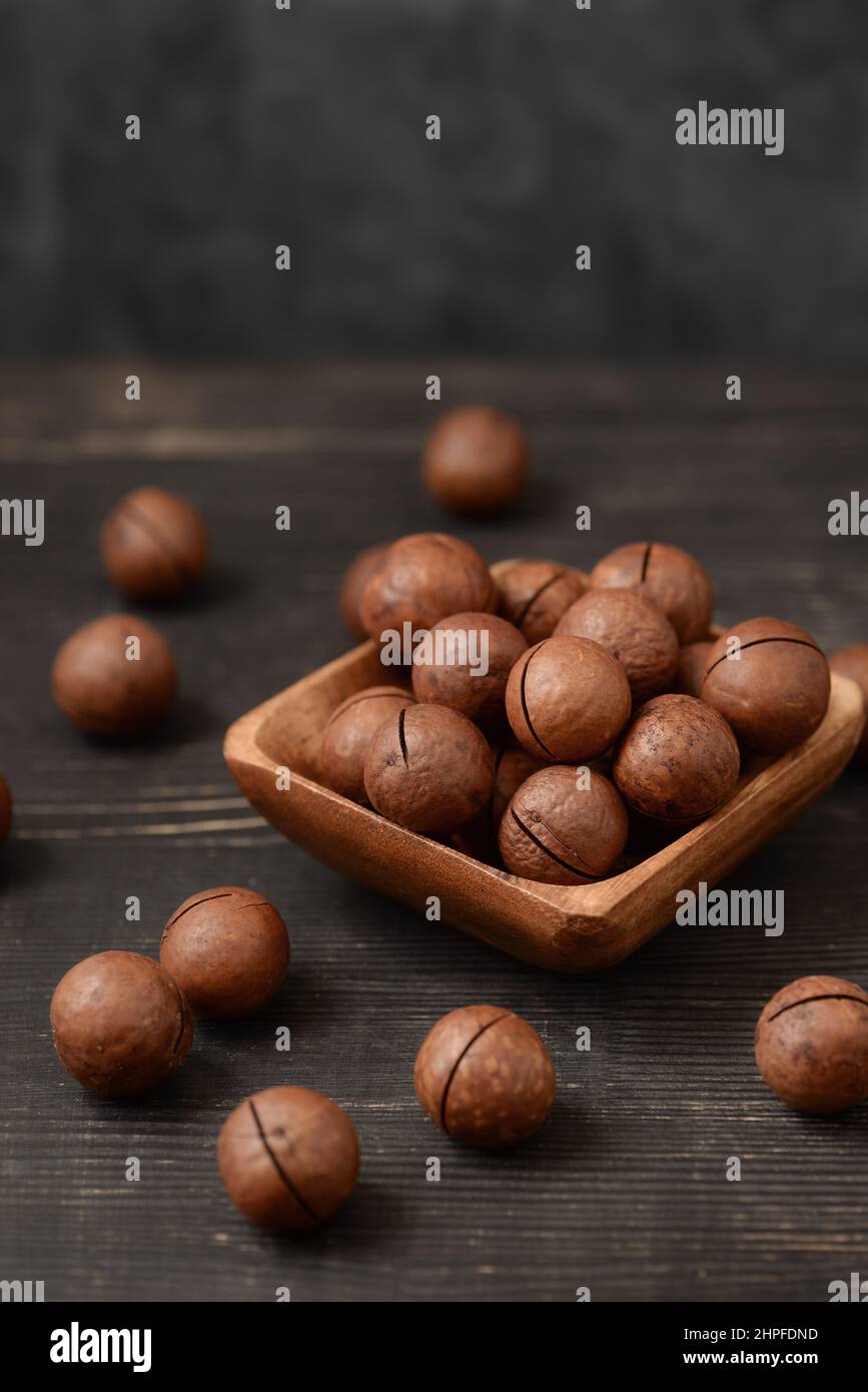 Schale mit Macadamia-Nüssen auf schwarzem Holztisch Stockfoto