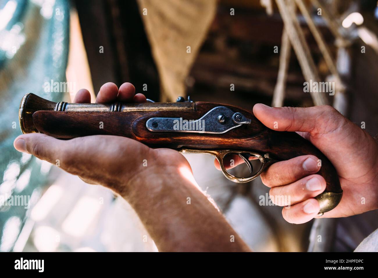 Alte Pistole mit einem Holzgriff in männlichen Händen. Mittelalterliche Waffen Stockfoto
