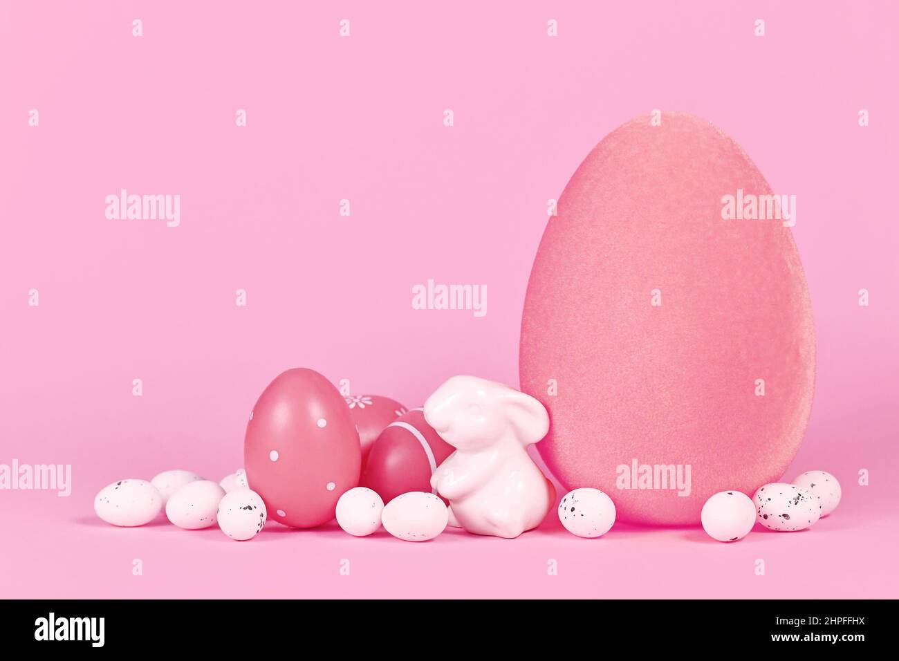 Ostereier und kleine Hase-Skulptur auf rosa Hintergrund mit Kopierraum Stockfoto