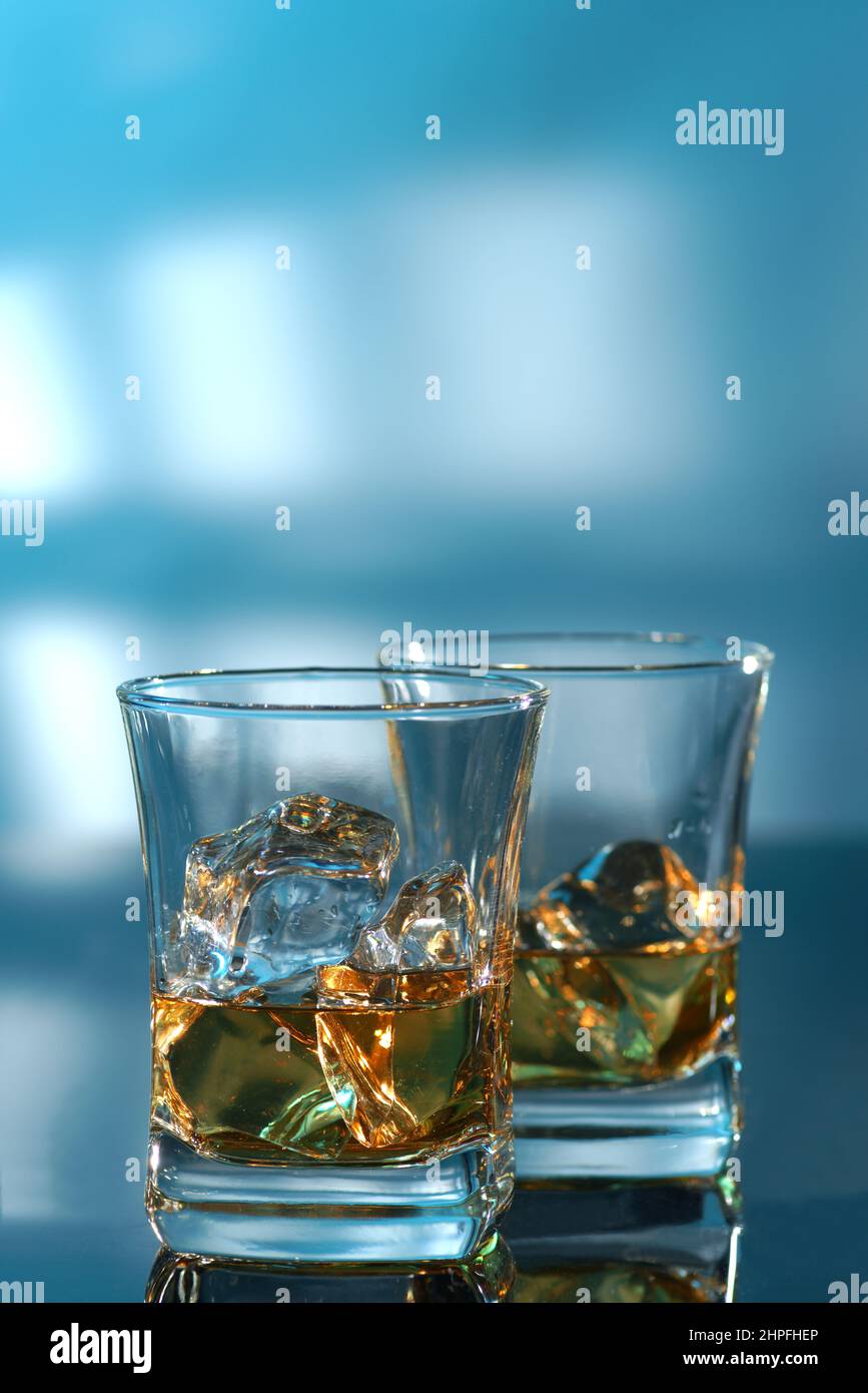 Ein Glas bernsteinfarbener Whiskey und Eis auf blauem Hintergrund Stockfoto