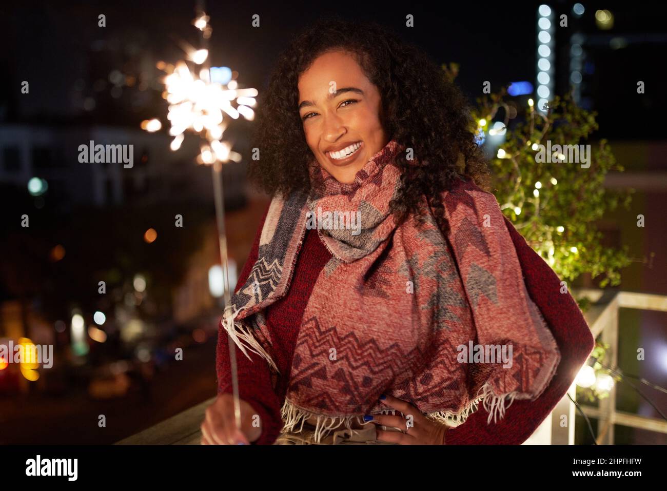 Porträt einer selbstbewussten, multirassischen Frau, die auf der Dachterrasse vor der Kamera lächelt. Nachtleben, gute Zeiten. Stockfoto