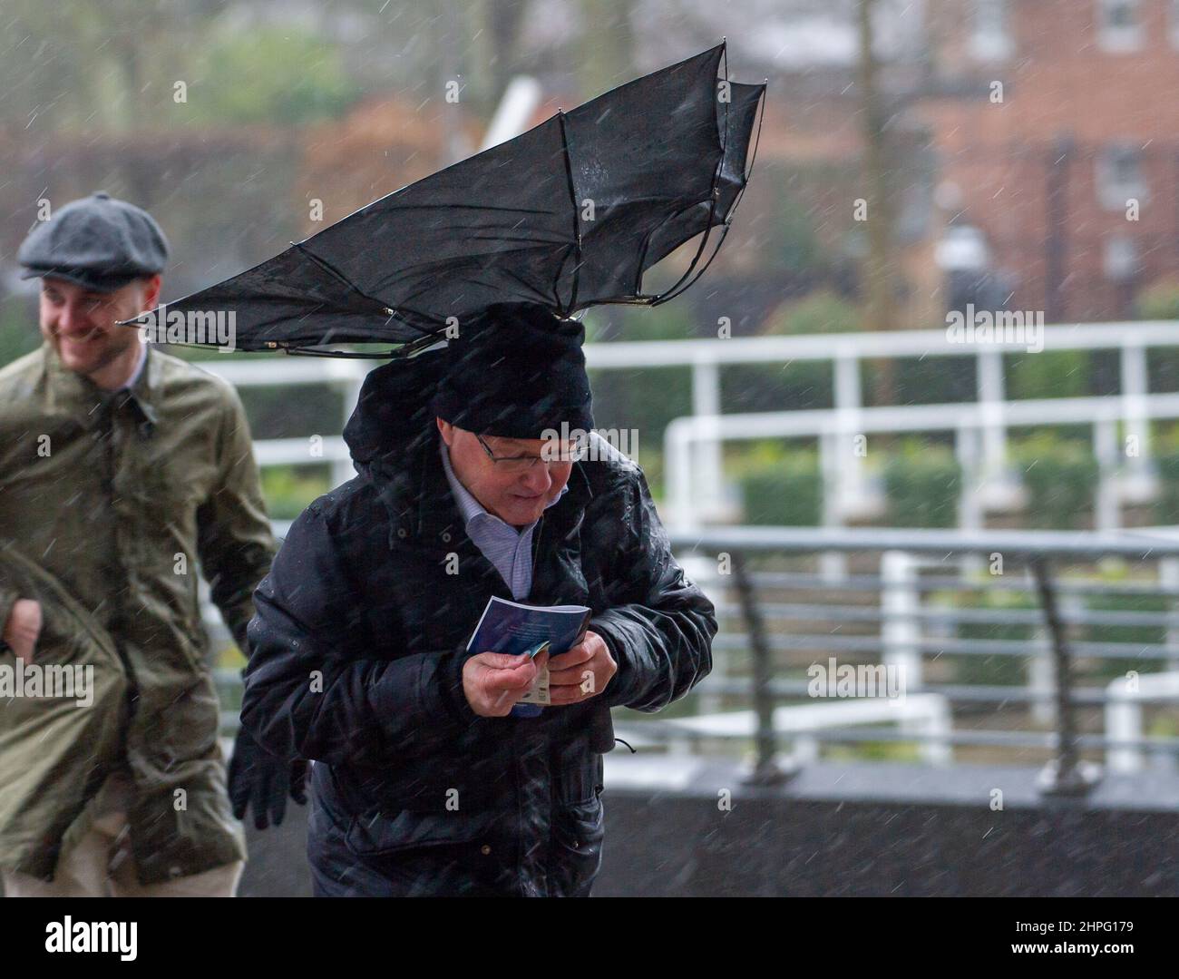 Ascot, Bergen, Großbritannien. 19th. Februar 2022. Racegoers, die am Betfair Ascot Chase Raceday teilnehmen, hatten heute nach dem Sturm Eunice bei starkem Wind und starkem Regen Probleme, ihre Regenschirme zu halten. Quelle: Maureen McLean/Alamy Stockfoto