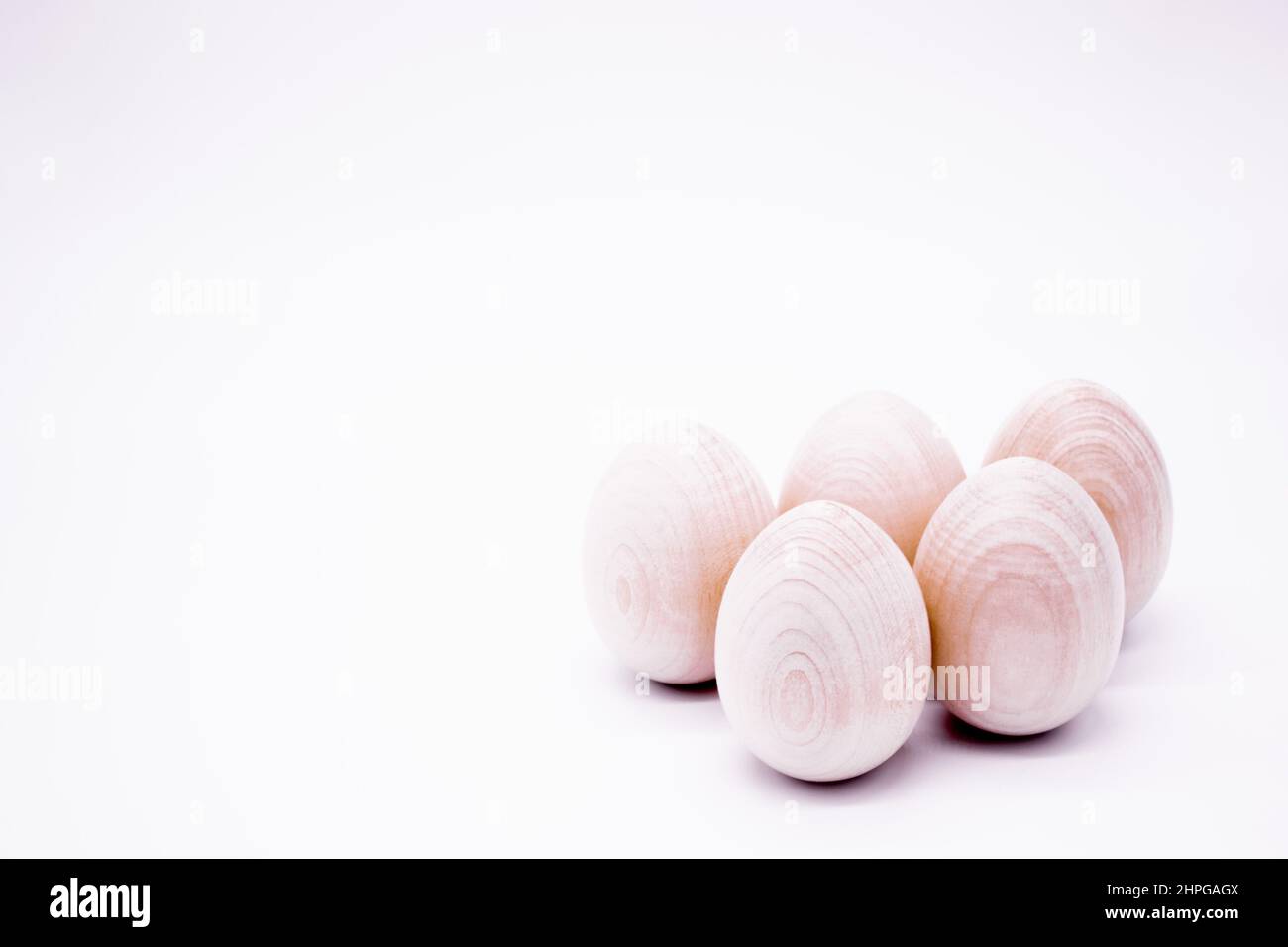 Fünf handgemachte, unbemalte Holzeier auf weißem Hintergrund. Speicherplatz kopieren. Stockfoto