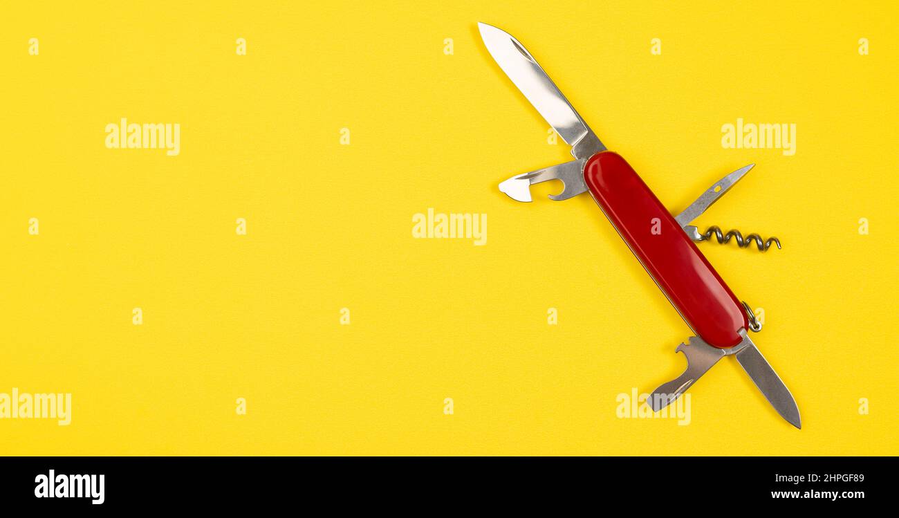 Jack of all Trades Konzept mit Swiss Army Multi Maut Taschenmesser isoliert auf gelbem Hintergrund. Rotes Militärmesser mit Kopierraum Stockfoto