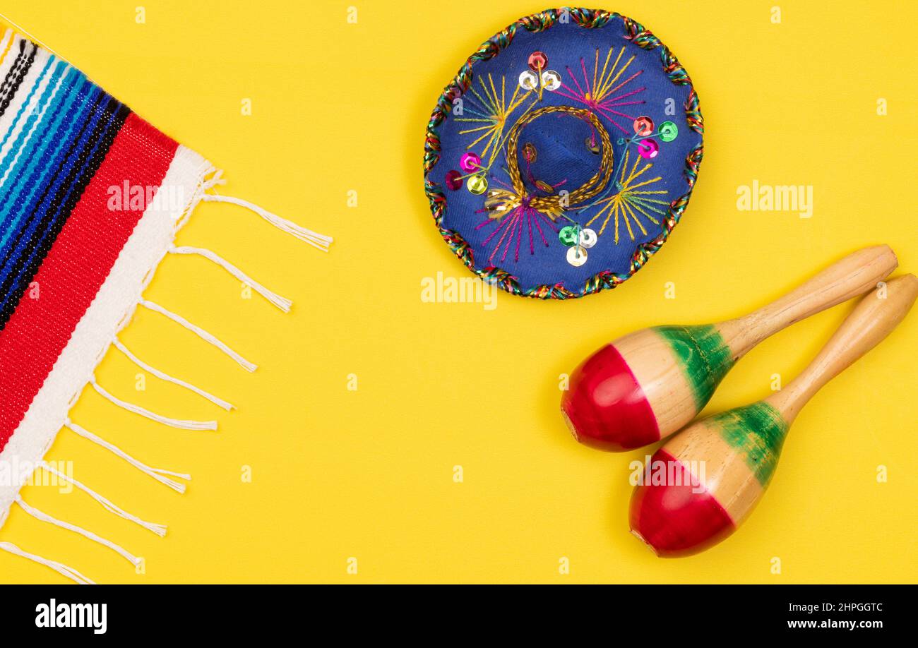 Farbenfroher Cinco de Mayo-Hintergrund mit traditionellem mexikanischen Serape, Sombrero und Marcas auf gelbem Hintergrund mit Kopierfläche Stockfoto