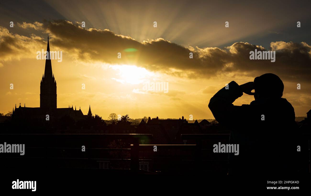 SALISBURY, GROSSBRITANNIEN. Ein Mann beobachtet den Sonnenuntergang über der Kathedrale von Salisbury bei viel ruhigeren Bedingungen nach Tagen starker Winde und heftiger Regenfälle in Wiltshire, Großbritannien. Datum: 21/02/2022. Kredit: Matthew Lofthouse/Alamy Live Nachrichten Stockfoto