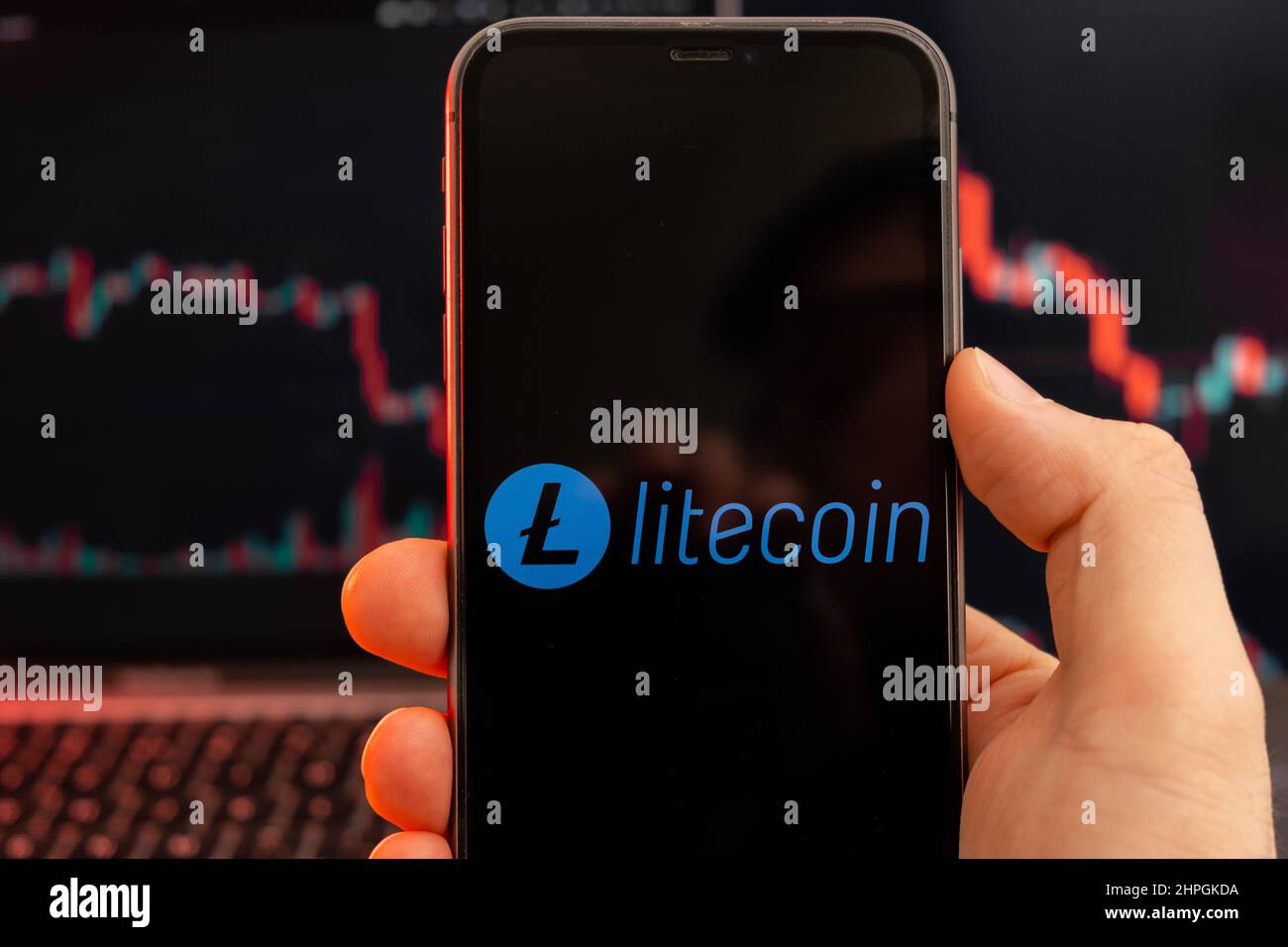 Litecoin LTC-App zur Analyse der Kryptowährung-Aktienmärkte auf dem Bildschirm von Mobiltelefonen in Menschenhand und Abwärtstrenddiagrammen, Handelsdaten im Hintergrund, Februar 2022, San Francisco, USA. Stockfoto