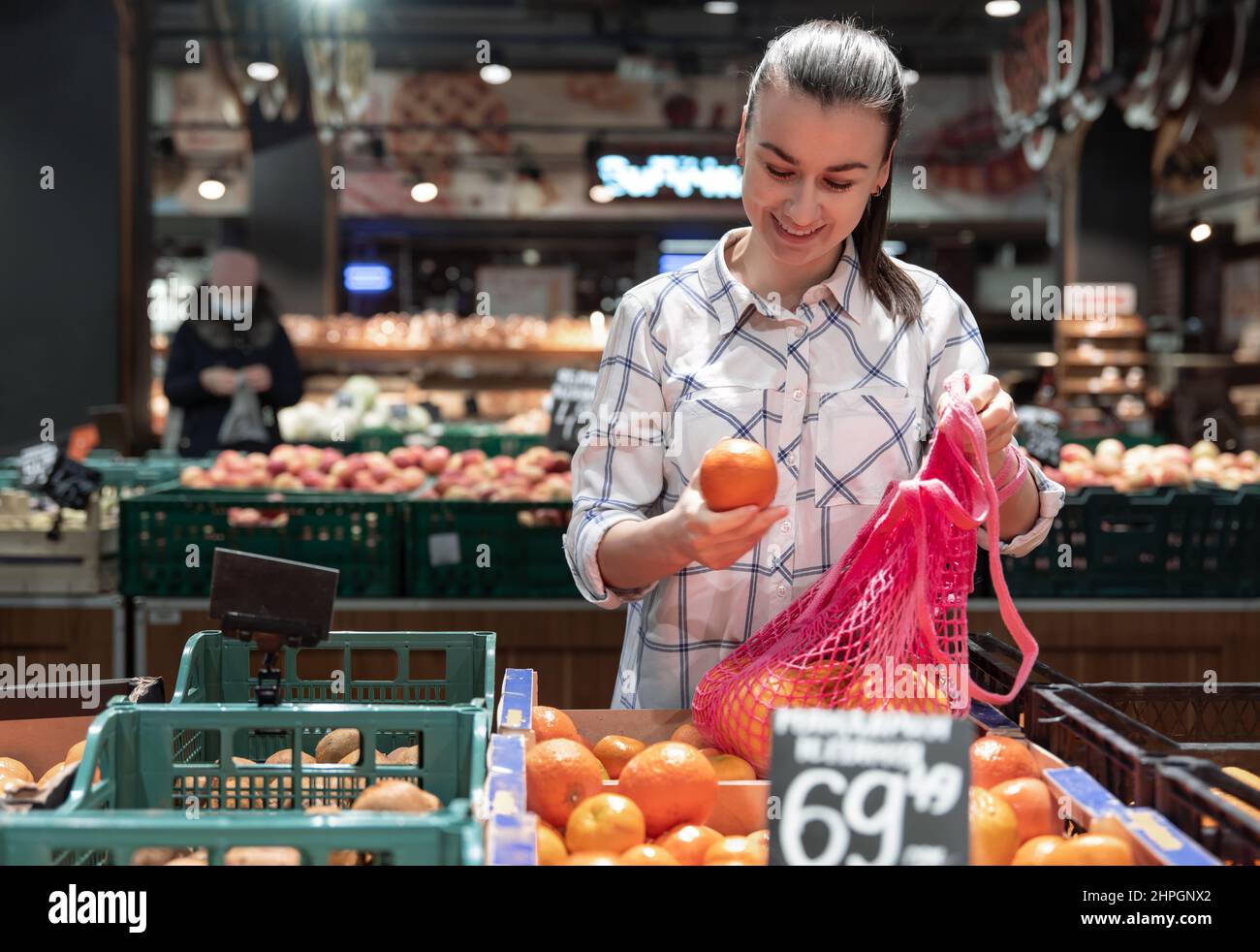Eine junge Frau wählt Früchte in einem Supermarkt. Stockfoto
