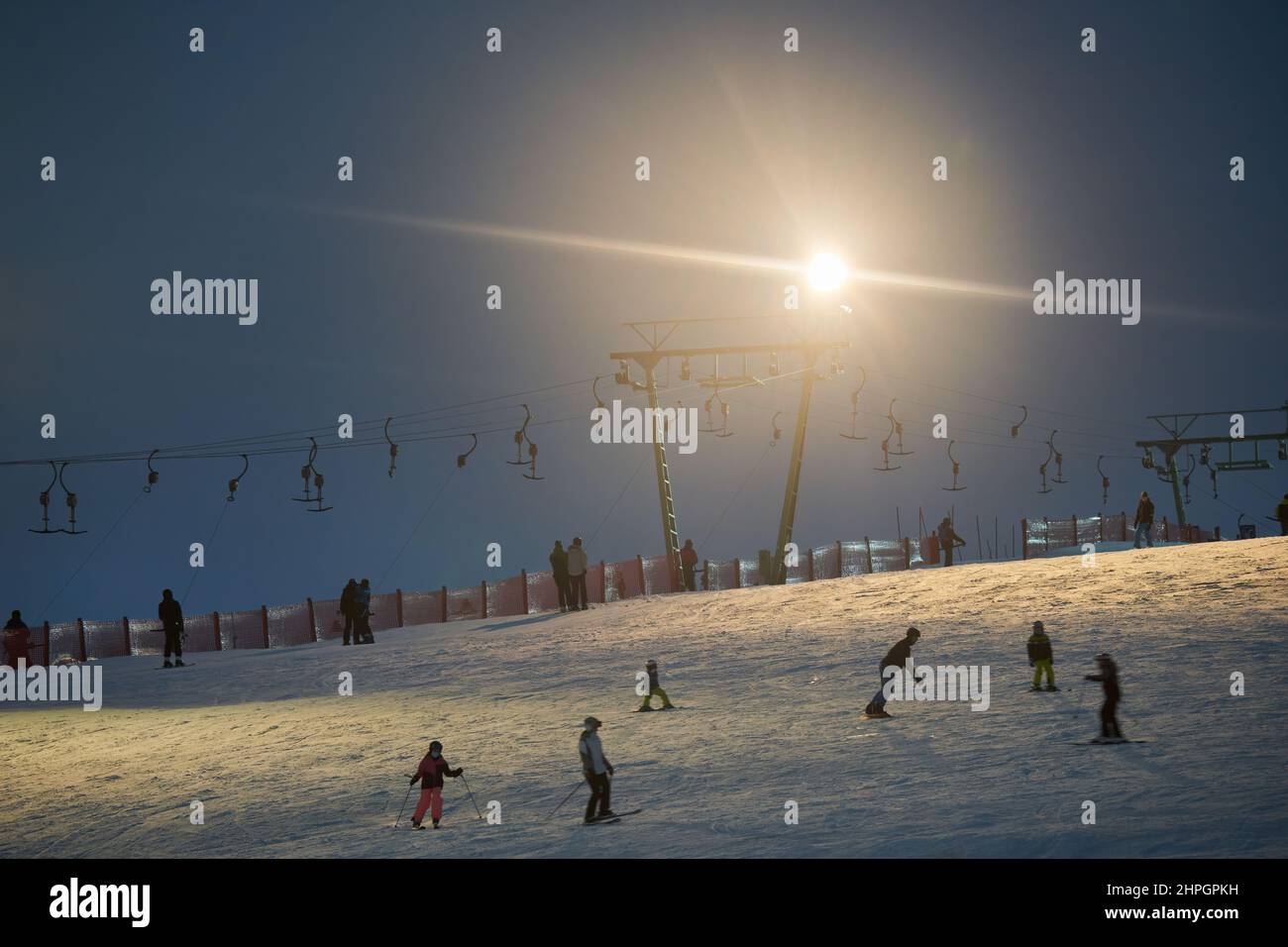 Treffelhausen, Deutschland - 28. Januar 2022: Schlepplift nachts mit Beleuchtung in Betrieb. Wintersportler auf den Pisten im Schnee. Männer und Frauen Stockfoto