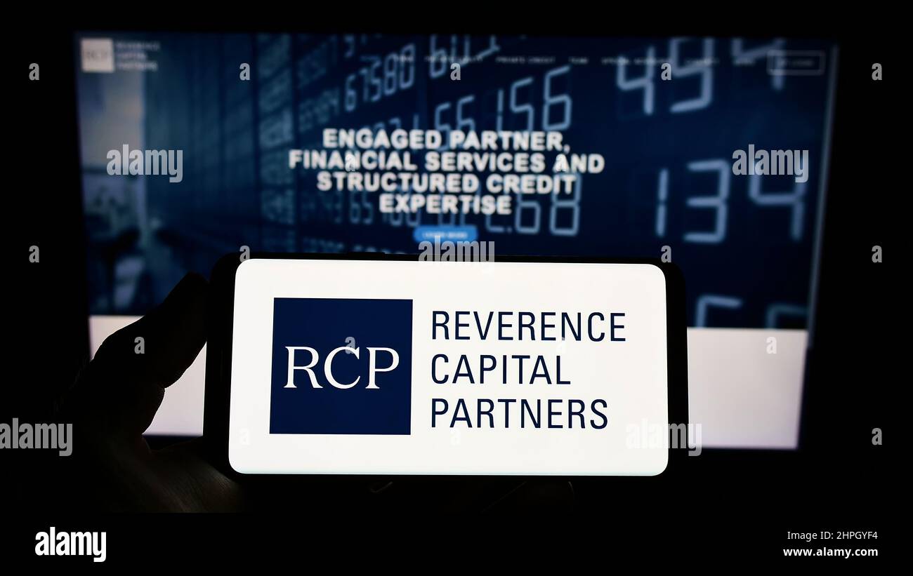 Person, die Smartphone mit dem Logo des US-Unternehmens Reverence Capital Partners L.P. hält (RCP) auf dem Bildschirm vor der Website. Konzentrieren Sie sich auf die Telefonanzeige. Stockfoto