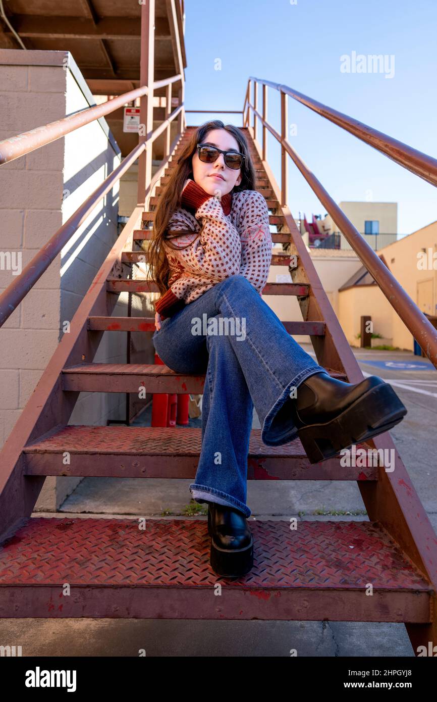 Junge Frau, die auf der Rusty Old Iron Staircase saß Stockfoto