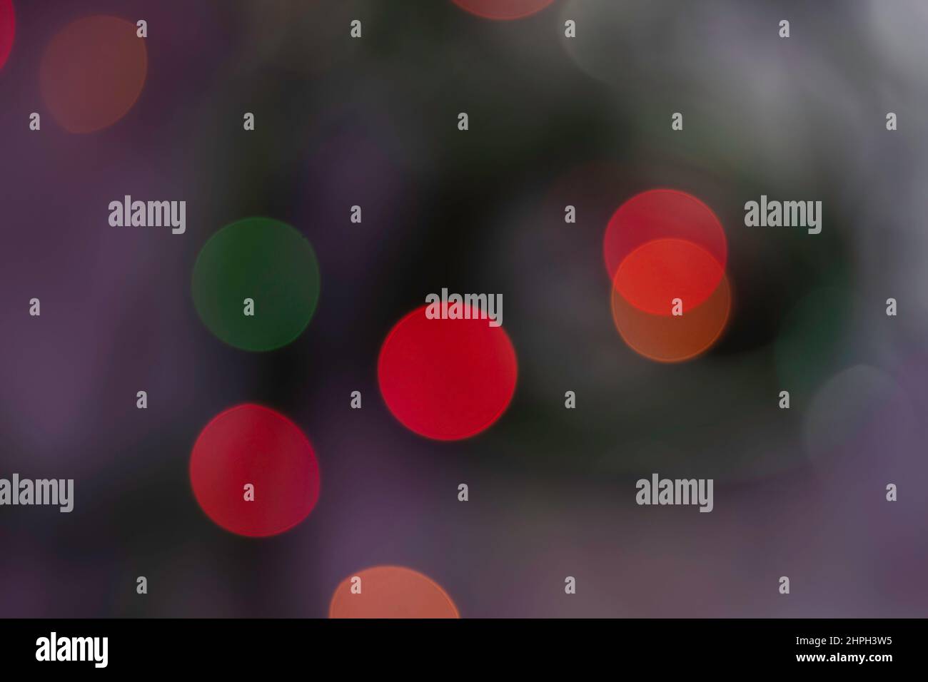 Abstrakter Bokeh-Hintergrund. Unscharf verwischte rote, orange, gelbe und grüne Farben leuchten auf dunklem Hintergrund Stockfoto