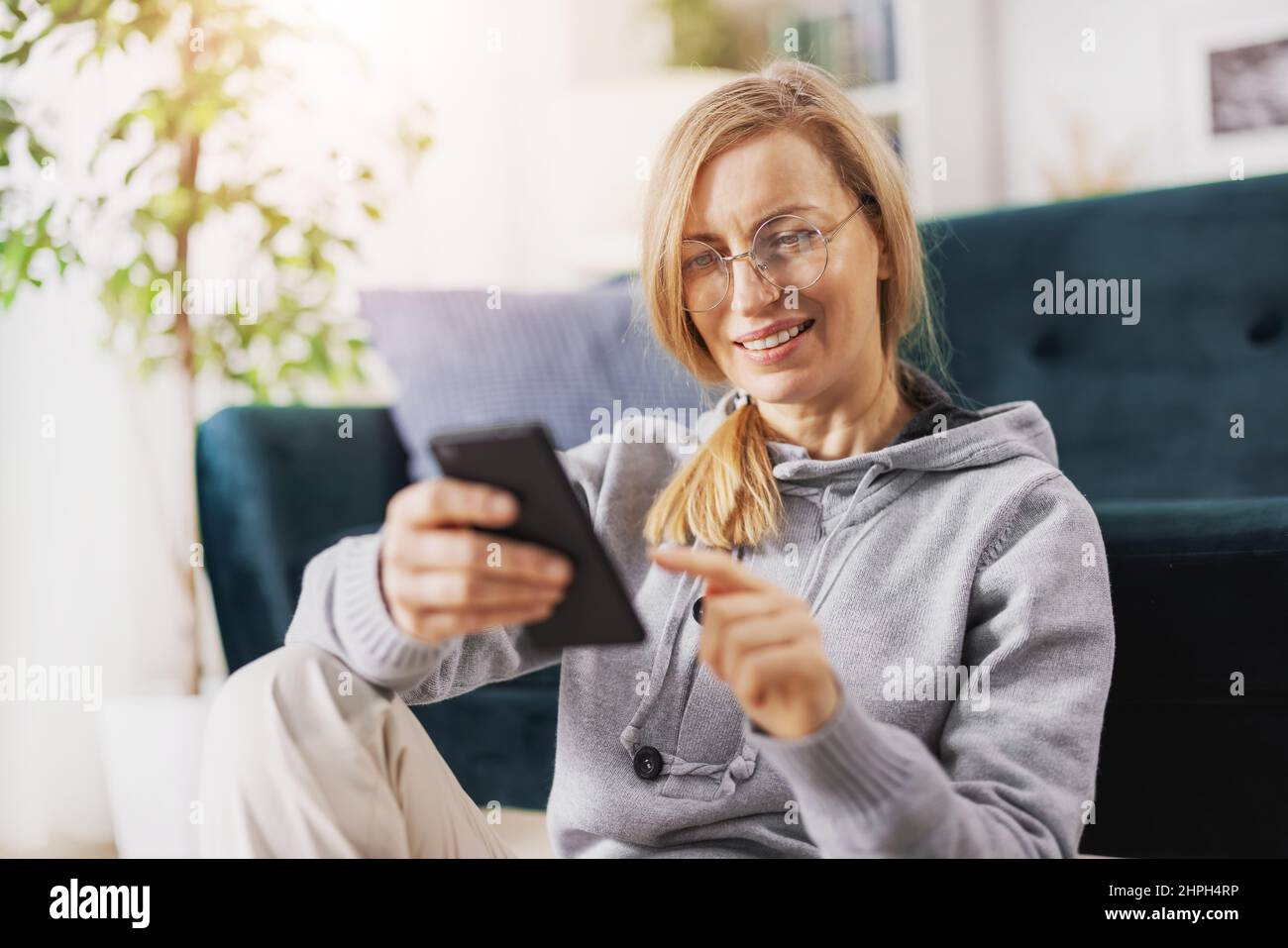 Blonde mit Smartphone zu Hause Stockfoto