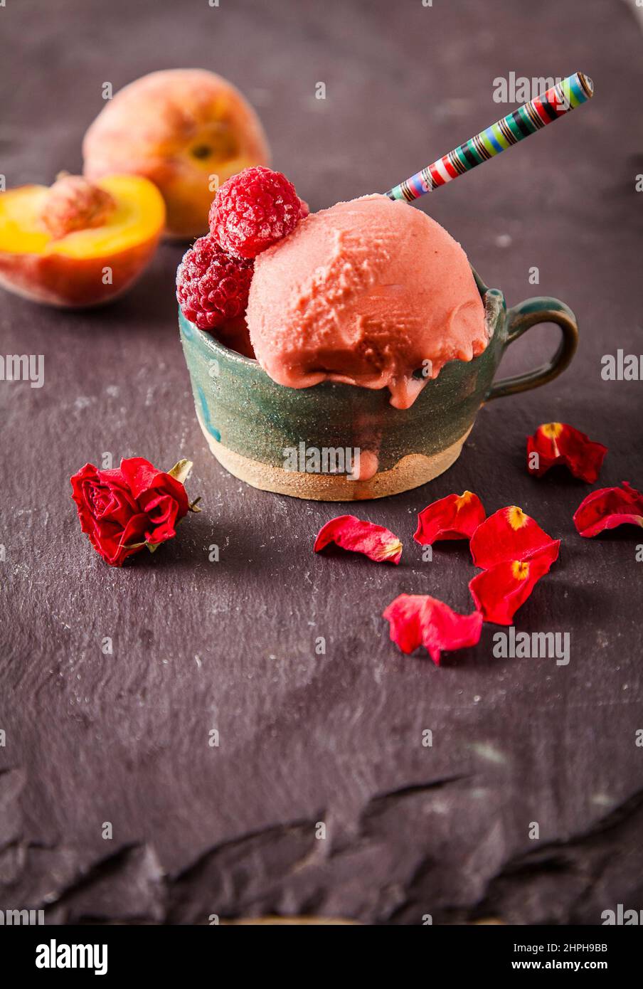 Italienisches Eis (Gelato) in einer Tasse mit Früchten auf Schiefergrund. Süßes und sommerliches Menükonzept. Stockfoto