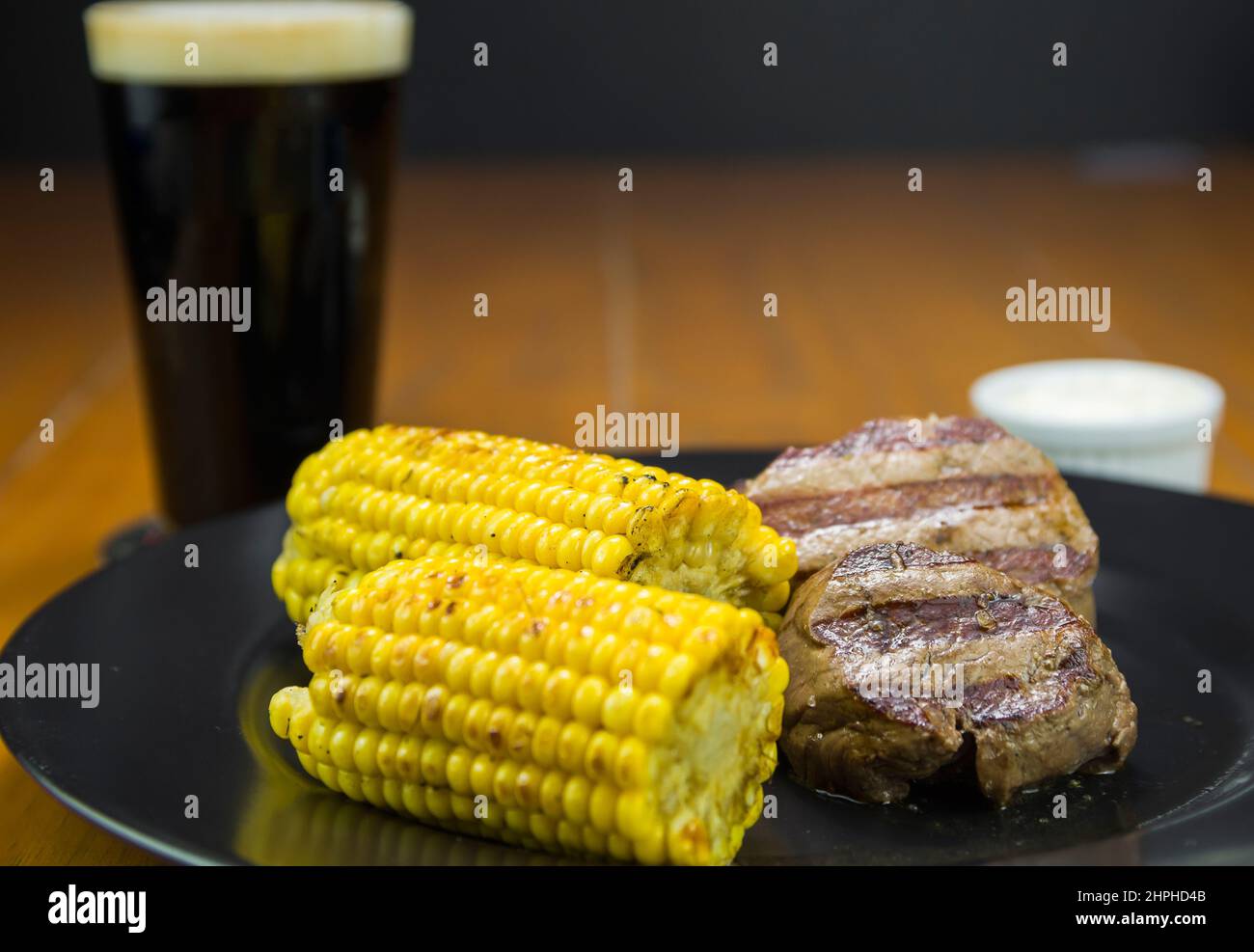 Köstliches Filet Mignon aus der Nähe mit geröstetem Mais und einem Glas Bier. Stockfoto