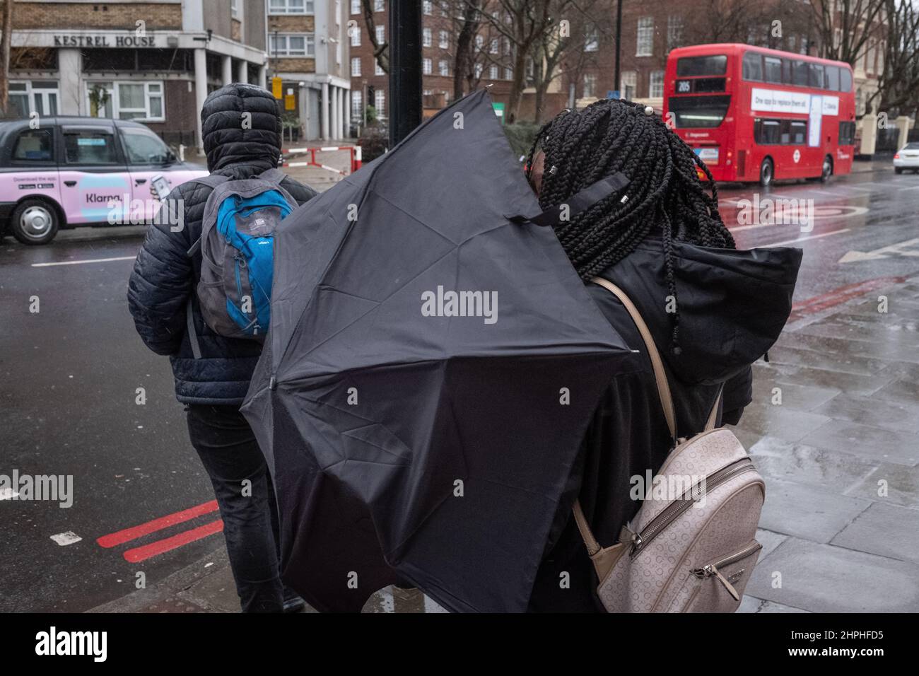 Eine Frau kämpft an einem stürmischen Tag in London, Großbritannien, mit Regenschirm Stockfoto