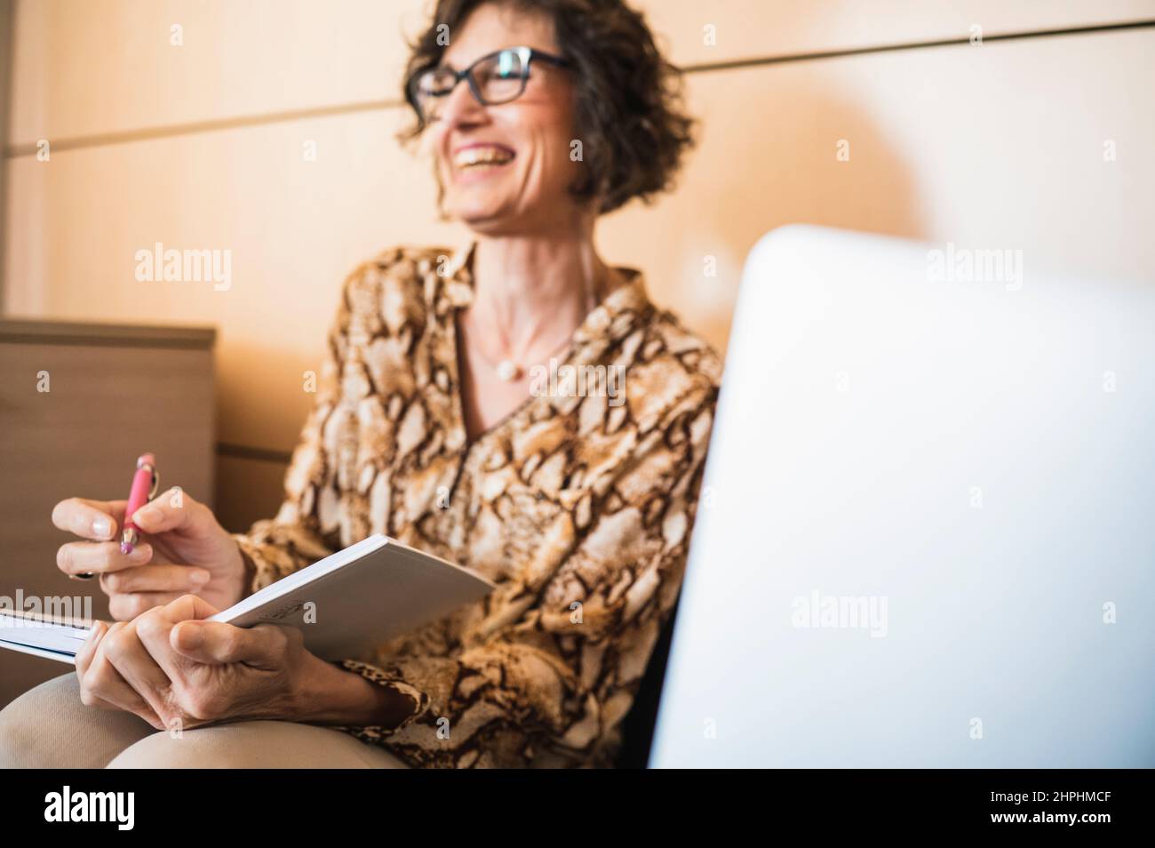 Ältere Frau lacht in einem Moment der Entspannung im Büro. Stockfoto